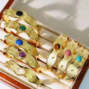 Vintage brede gehamerde gouden armbanden met kleurrijke ovale edelstenen in een houten doos