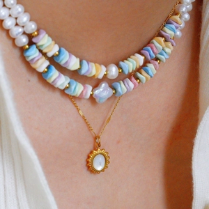Detailopname van een drielaagse ketting met parels en kleurrijke kralen op een model