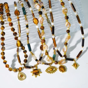Détail de colliers bohèmes en perles d'œil de tigre avec pendentifs soleil dorés