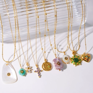 Baroque pearl and shell stainless steel necklace set with diverse gold charms on white surface