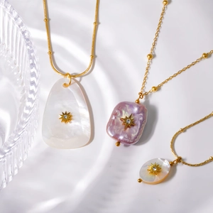 Baroque pearl and shell pendant necklace set with gold starburst and zircon charms