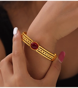 Détail de la manchette rétro dorée avec insert en pierre rouge et motif chaîne ajourée