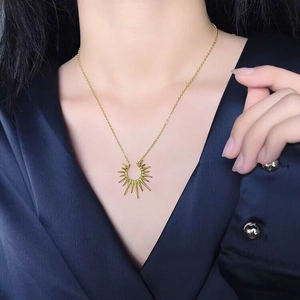 Collier à pendentif soleil doré porté par un mannequin en chemise de satin bleu foncé