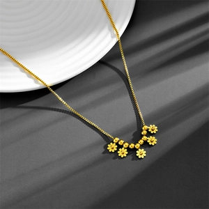 Detail of golden box chain necklace with delicate daisy pendants and bead accents