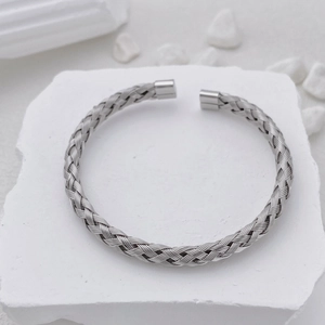 Detail of woven stainless steel bracelet texture with polished ends on stone surface