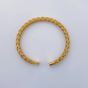 Close-up of golden braided titanium steel cuff bracelet with detailed woven texture