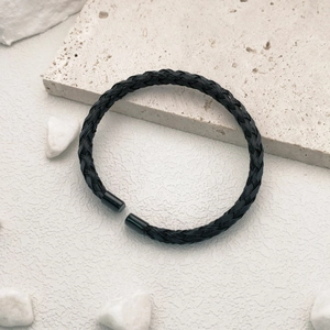 Macro detail of black braided titanium steel open cuff bracelet on stone background