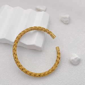 Detailed close-up of a gold woven mesh open bangle with smooth cylindrical end caps