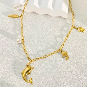 Detailed macro view of 18k gold plated ocean charms and white pearl on necklace