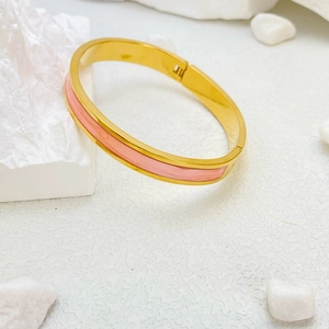 Bracciale rigido in acciaio al titanio dorato con smalto rosa in una vetrina di lusso
