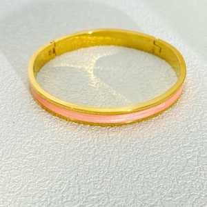 Dettaglio dell'intarsio in smalto rosa su un bracciale in acciaio inossidabile placcato oro