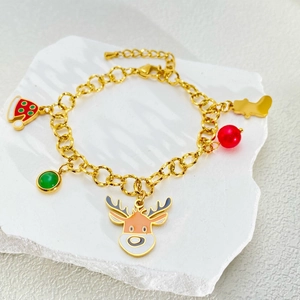 Detailopname van een gouden kerstarmband met feestelijke bedeltjes van rendieren en mutsen