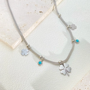 Detail of woven mesh titanium steel chain with clover and turquoise pendants