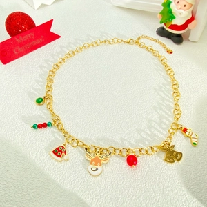 Detail van gouden kerstketting met emaille rendier en bel hangers op een witte achtergrond