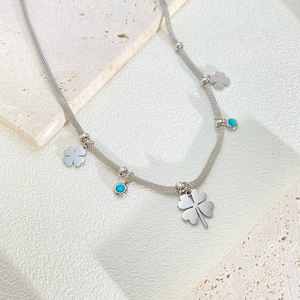 Detailed shot of mesh woven titanium steel chain with clover and turquoise pendants