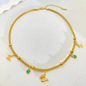 Close-up of golden mesh chain necklace featuring butterfly charms and turquoise beads