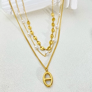 Close-up of gold triple-layered necklace with pearls and hollow oval pendant