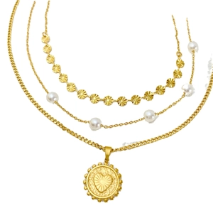 Three-layer gold titanium necklace with sequins, pearls and a heart pendant on white background