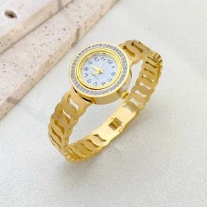 Detail of a gold stainless steel watch with hollow band and rhinestone bezel