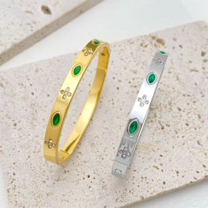 Detailed view of gold and silver clover bangles with emerald stones and inlaid diamonds