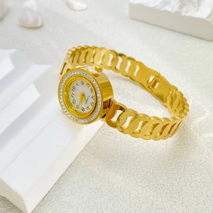 Detail of elegant gold-tone watch with crystal bezel and hollow chain bracelet on pedestal