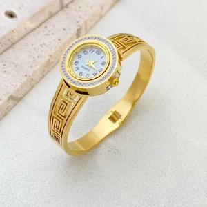 Detail of gold-plated bangle watch with Greek key pattern and crystal bezel
