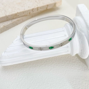 Detail of silver titanium steel bracelet with emerald gems and clover diamond pavé