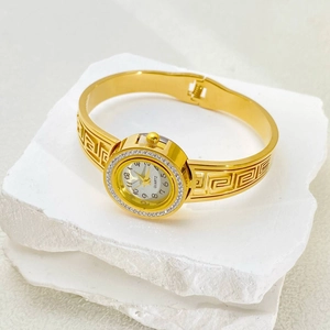 Macro view of gold stainless steel watch band with hollow Greek Key pattern and crystals