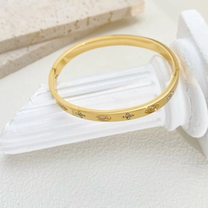 Detail of polished gold bangle with marquise gems and diamond flower patterns