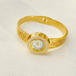 Detailed view of elegant gold bangle watch featuring rhinestone bezel and Greek meander pattern