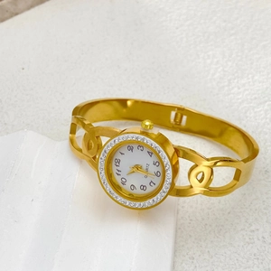 Detail of elegant gold hollow bangle watch with crystal bezel and quartz dial