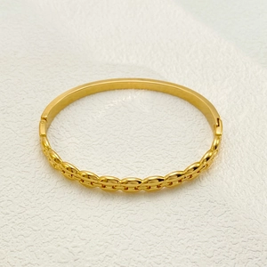 Detail view of gold stainless steel bangle with polished and coffee bean textured surface