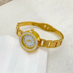 Macro shot of gold quartz watch featuring a crystal bezel and Arabic numeral dial