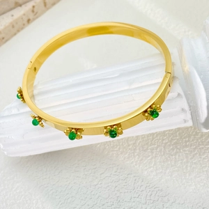 Detailed macro view of 18K gold plated sunflower bracelet with emerald green gemstones