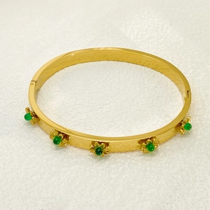 Detailed close-up of 18K gold plated sunflower bracelet with green gemstone inlays