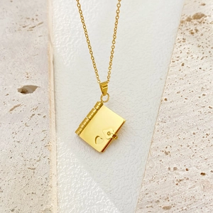 Macro detail of 18k gold plated book locket pendant with a delicate heart hollow design