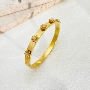 Detailed macro view of 18K gold-plated sunflower bracelet with pink crystal flower centers