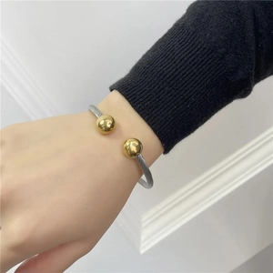 Close-up of titanium cable bracelet with gold-plated spheres on a model's wrist