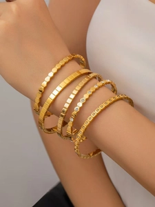 Close-up of layered 18K gold plated titanium steel bracelets with zircon inlay and honeycomb texture