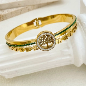 Detailed view of Tree of Life gold bangle with sparkling green gems and white zircons