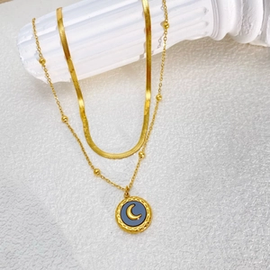 Elegant gold double-layer snake chain necklace featuring a black moon pendant on a stone pillar