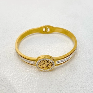 Macro detail of gold-plated tree of life bangle with white crystals on a white surface