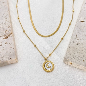 Detail of layered gold moon necklace featuring sleek snake chain and shell pendant