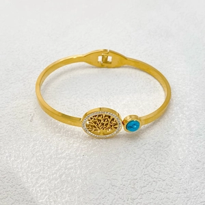 Detail of gold tree of life bangle with hinge closure, white crystals and turquoise gem