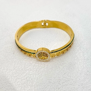 Close-up of golden Tree of Life bangle featuring white zircons and green rhinestone accents