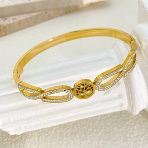 Detail of gold tree of life bangle with white rhinestones on marble pillar