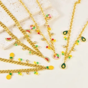 Detail of gold necklaces with colorful enamel summer fruit charms and sparkling crystals