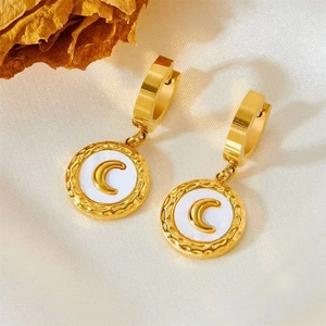 Close-up of gold huggie earrings featuring white enamel and crescent moon charms