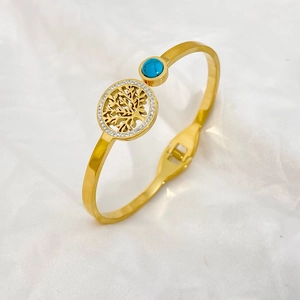 Detailed macro view of gold tree of life bangle with turquoise stone and sparkling rhinestones