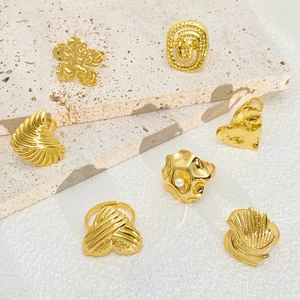 Collection of seven organic-shaped golden rings with pearl accent on light stone surface